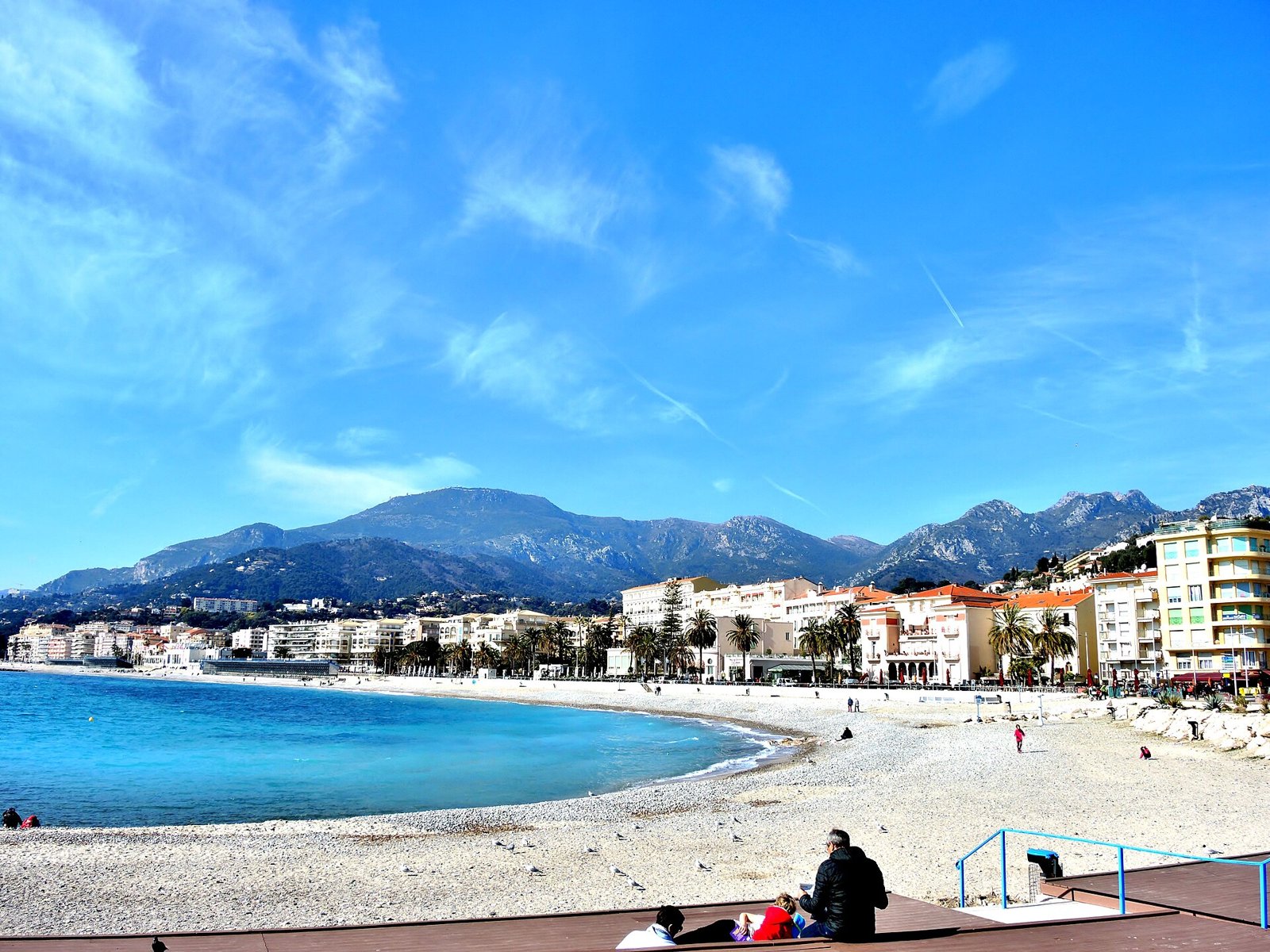 Plage de Menton au calme devant la Promenade du Soleil, avec les montagnes en arrière-plan